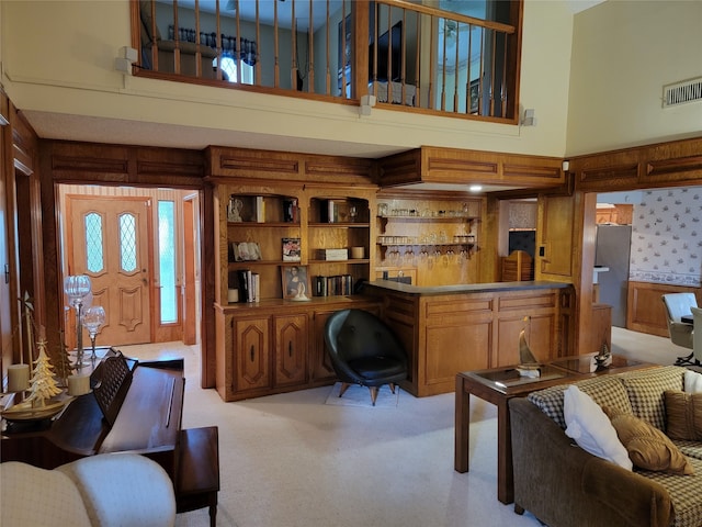 carpeted living room with a high ceiling and wooden walls