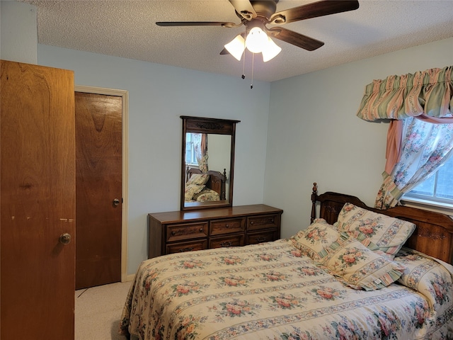 carpeted bedroom featuring ceiling fan and a textured ceiling