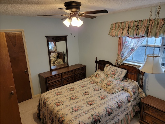 carpeted bedroom featuring ceiling fan and a textured ceiling