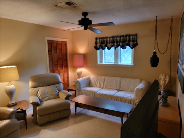 carpeted living room featuring ceiling fan and a textured ceiling