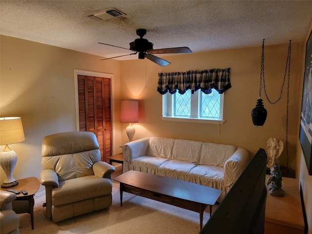 living room featuring ceiling fan and a textured ceiling