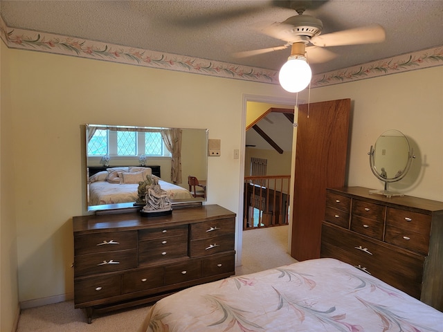 bedroom with ceiling fan, a textured ceiling, and light carpet