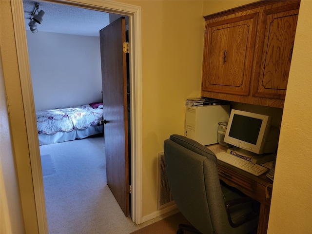 home office with a textured ceiling, light colored carpet, and rail lighting