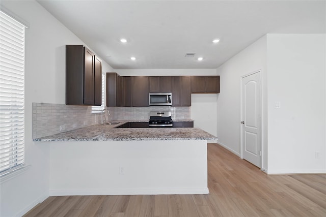 21214 Montego Bay Dr, Cypress, TX 77433 - kitchen featuring stainless steel appliances, a sink, dark brown cabinetry, decorative backsplash, and light wood-style floors