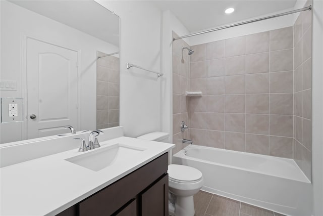 full bathroom featuring tile patterned flooring, vanity, tiled shower / bath combo, and toilet