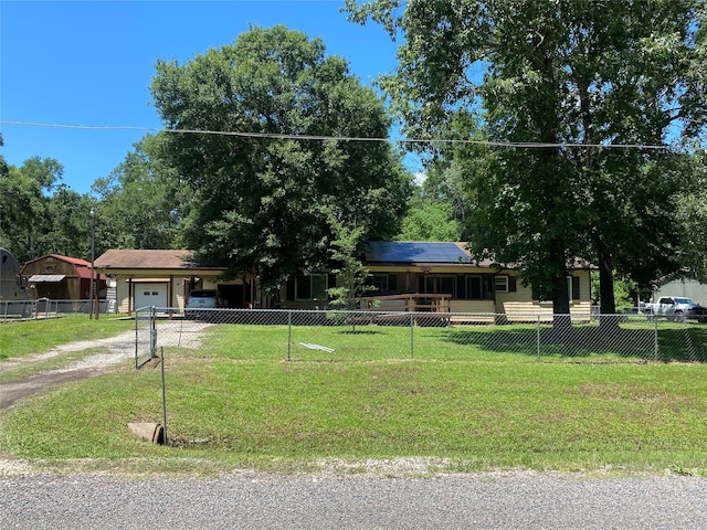 view of front of home featuring a garage, a front lawn, and solar panels