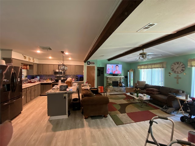 living room with ceiling fan, beam ceiling, a fireplace, and light wood-type flooring