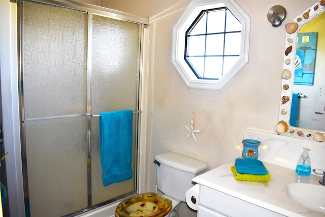 bathroom featuring a shower with door, vanity, and toilet