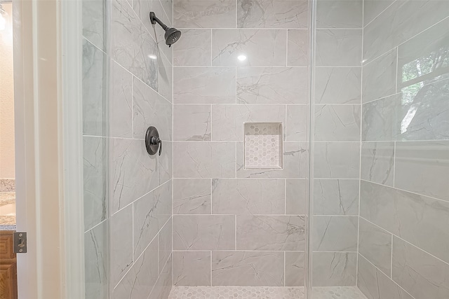 bathroom with tiled shower and vanity