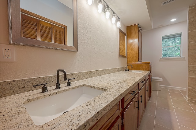 bathroom featuring tile floors, oversized vanity, toilet, and double sink