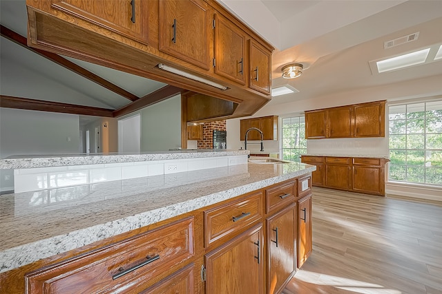 kitchen featuring light hardwood / wood-style floors, sink, backsplash, and light stone counters