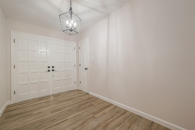 foyer entrance with an inviting chandelier and wood-type flooring