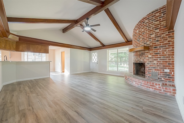 unfurnished living room featuring beam ceiling, a fireplace, ceiling fan, and light hardwood / wood-style flooring