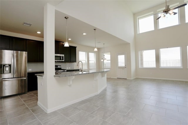 kitchen with light tile flooring, hanging light fixtures, ceiling fan, tasteful backsplash, and appliances with stainless steel finishes