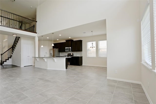 unfurnished living room with a high ceiling, sink, and light tile floors