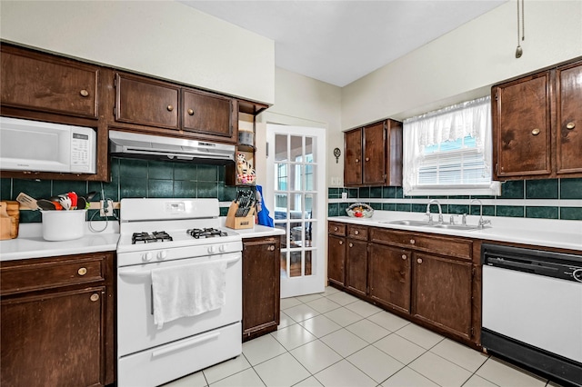 kitchen featuring white appliances, dark brown cabinetry, sink, and decorative backsplash