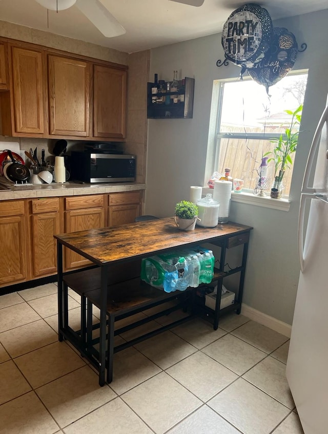 kitchen with light tile patterned floors, ceiling fan, and white refrigerator