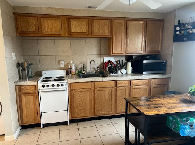 kitchen with light tile patterned flooring, white electric range oven, sink, ceiling fan, and backsplash