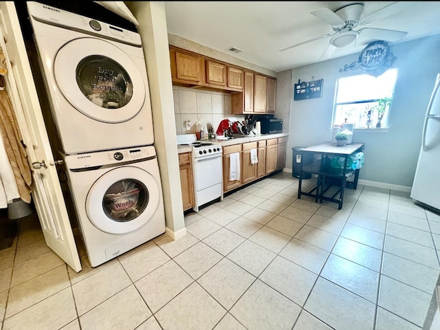 kitchen with light tile patterned flooring, stacked washer and dryer, ceiling fan, white appliances, and backsplash