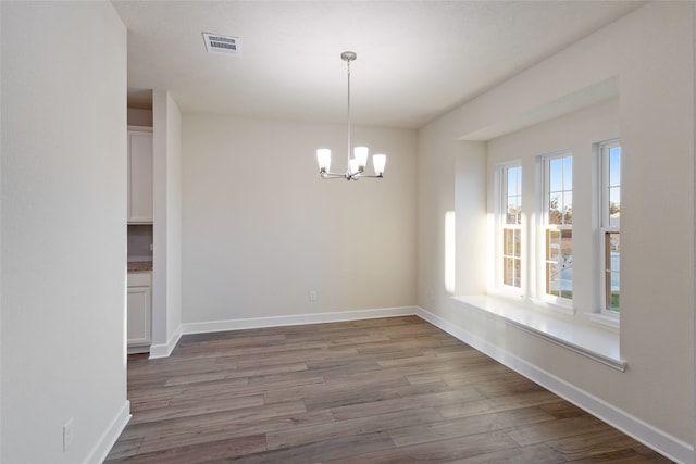 unfurnished dining area featuring hardwood / wood-style floors and a chandelier