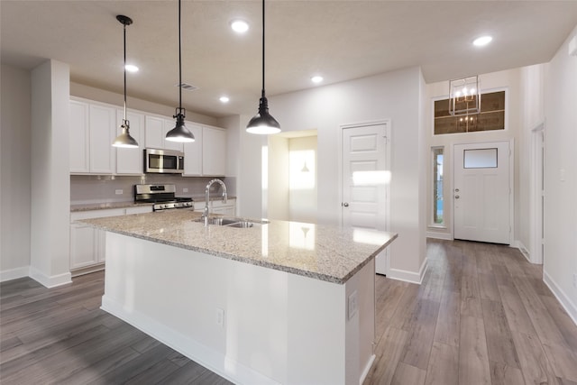 kitchen with white cabinets, an island with sink, light hardwood / wood-style flooring, sink, and stainless steel appliances