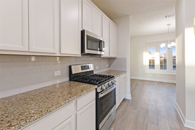 kitchen featuring decorative backsplash, light stone counters, white cabinetry, light hardwood / wood-style flooring, and stainless steel appliances