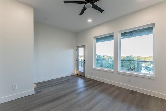 spare room with a healthy amount of sunlight, ceiling fan, and dark hardwood / wood-style flooring