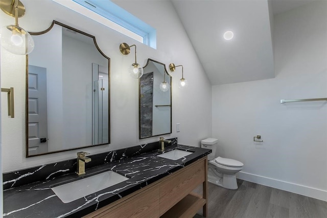 bathroom with dual vanity, vaulted ceiling, hardwood / wood-style flooring, and toilet