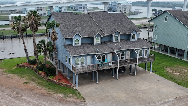 view of front facade featuring a water view, a carport, and a front lawn