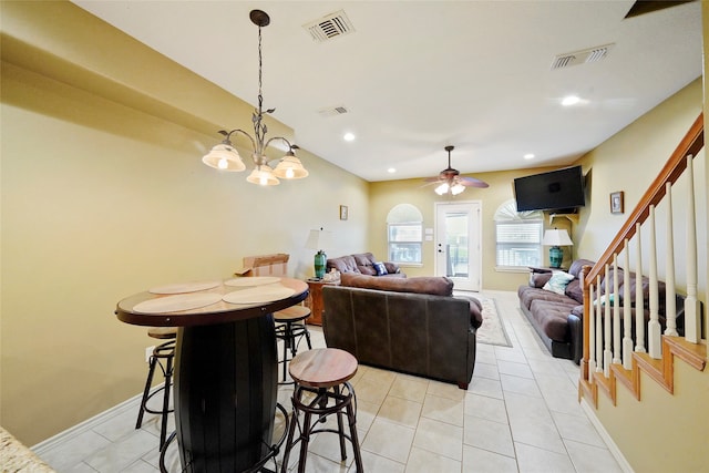 dining area featuring light tile floors and ceiling fan with notable chandelier