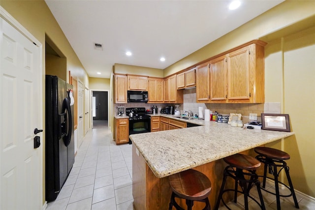 kitchen with kitchen peninsula, backsplash, black appliances, sink, and light tile floors