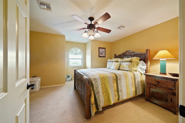 bedroom with light colored carpet, ceiling fan, and a textured ceiling