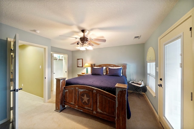 carpeted bedroom featuring ceiling fan and a textured ceiling