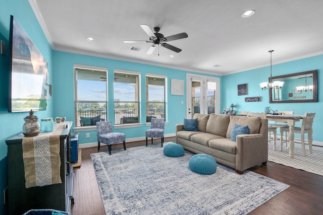 living room with plenty of natural light, ceiling fan with notable chandelier, ornamental molding, and dark wood-type flooring