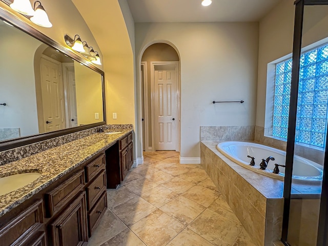 bathroom featuring tile floors, a relaxing tiled bath, and vanity with extensive cabinet space