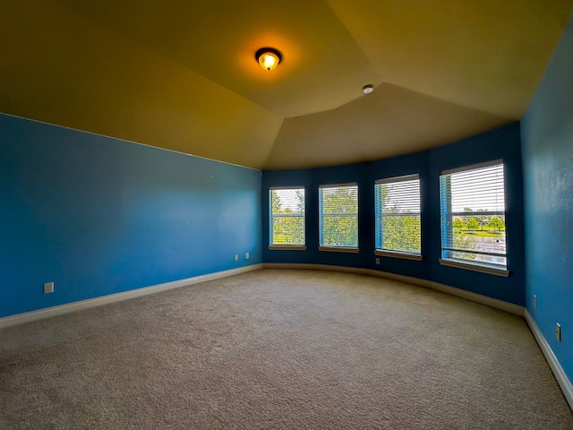 carpeted spare room with vaulted ceiling