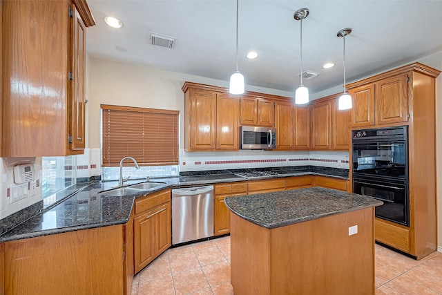 kitchen featuring appliances with stainless steel finishes, decorative light fixtures, a kitchen island, and sink