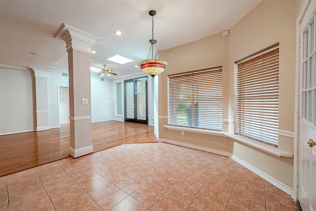 tiled empty room featuring ceiling fan, french doors, crown molding, and decorative columns