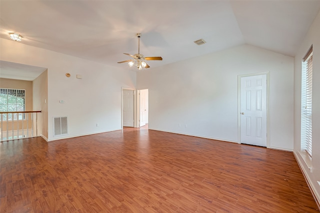 empty room featuring ceiling fan, vaulted ceiling, a wealth of natural light, and wood-type flooring