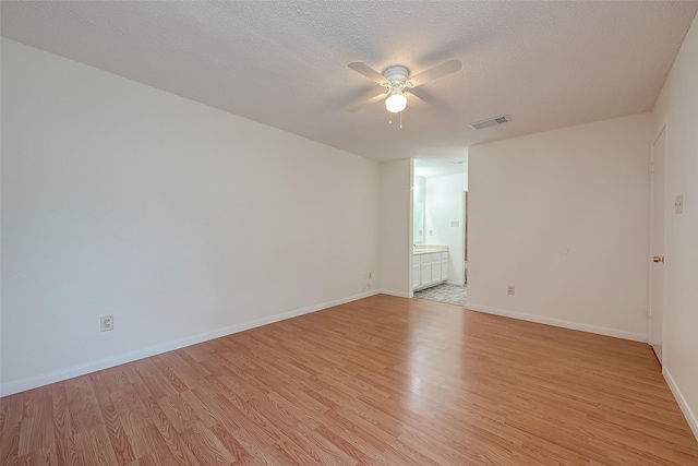 empty room with a textured ceiling, light wood-type flooring, and ceiling fan