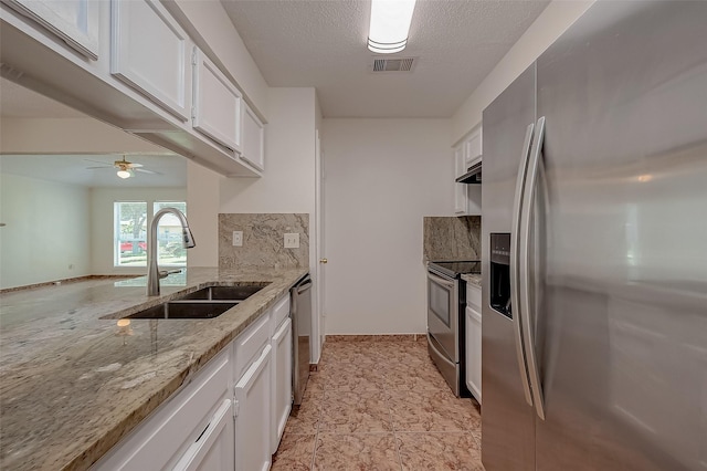 kitchen with light stone countertops, white cabinetry, sink, and appliances with stainless steel finishes