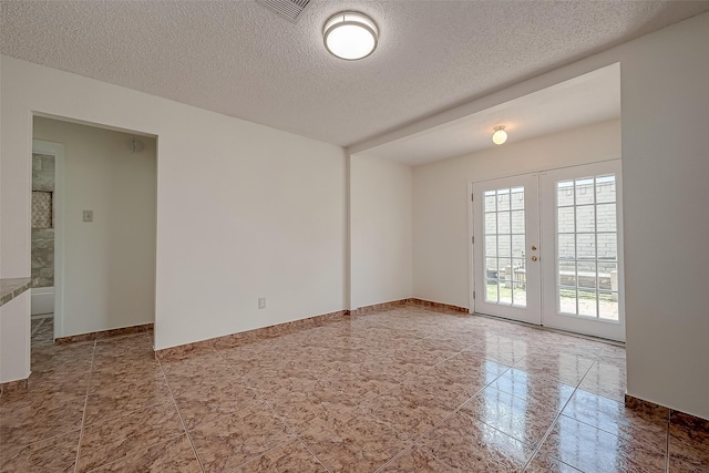 tiled empty room with french doors and a textured ceiling