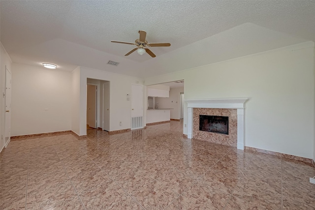 unfurnished living room with a tile fireplace, a textured ceiling, and ceiling fan