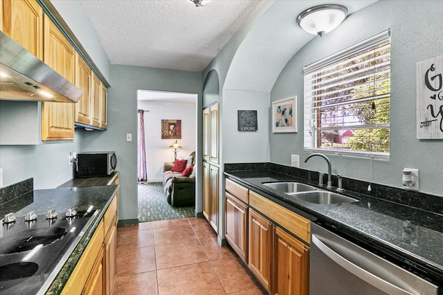 kitchen with wall chimney range hood, sink, stainless steel appliances, and light tile floors