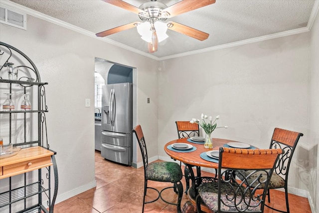 tiled dining space featuring a textured ceiling, ceiling fan, and crown molding