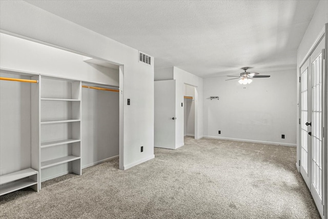 unfurnished bedroom with light carpet, a textured ceiling, and ceiling fan