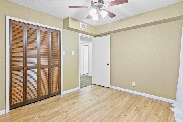 unfurnished bedroom with ceiling fan, a closet, a textured ceiling, and light colored carpet