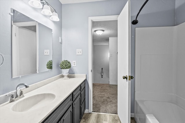 bathroom featuring  shower combination, a textured ceiling, hardwood / wood-style flooring, and vanity