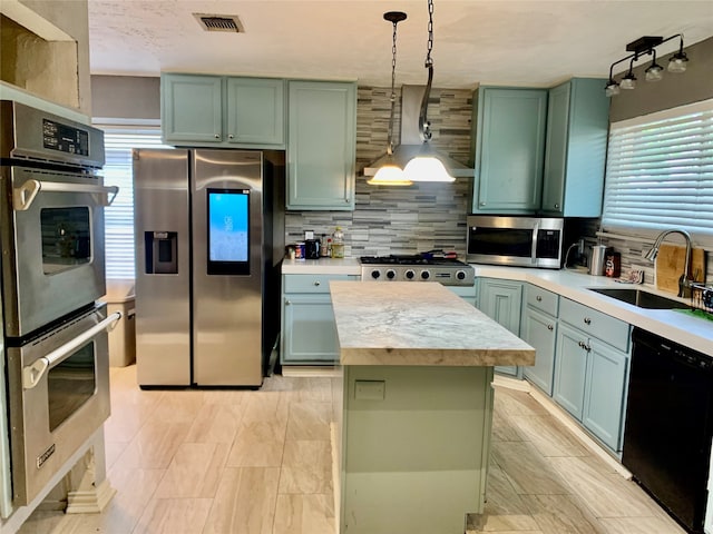 kitchen with a kitchen island, appliances with stainless steel finishes, wall chimney exhaust hood, backsplash, and sink