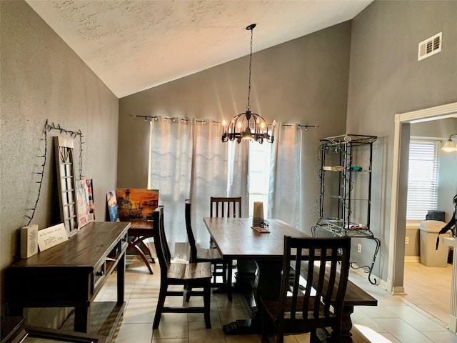 tiled dining room featuring high vaulted ceiling and a chandelier